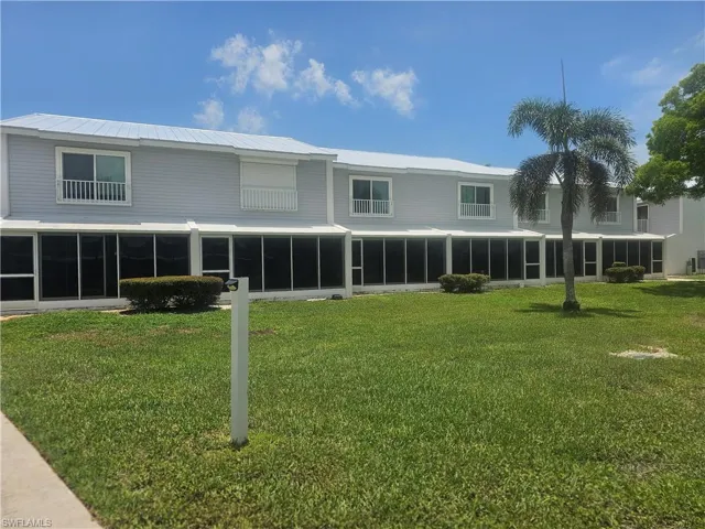 Rear view of property featuring a sunroom, a yard, and a metal roof