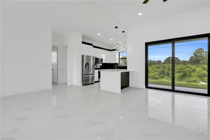 Kitchen with stainless steel refrigerator with ice dispenser, white cabinets, decorative light fixtures, modern cabinets, and light marble finish flooring