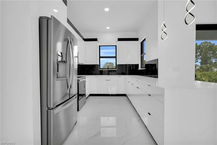 Kitchen with stainless steel refrigerator with ice dispenser, modern cabinets, range with electric cooktop, light marble finish floors, and recessed lighting