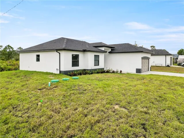 View of front facade with an attached garage, a front lawn, stucco siding, and concrete driveway