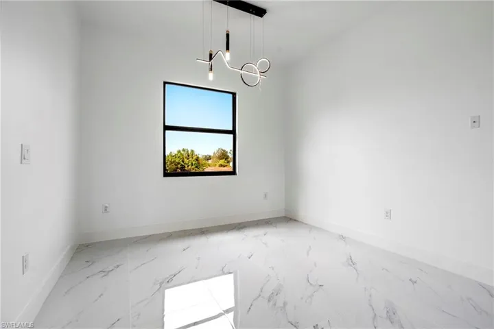 Spare room featuring baseboards, marble finish floor, and a notable chandelier