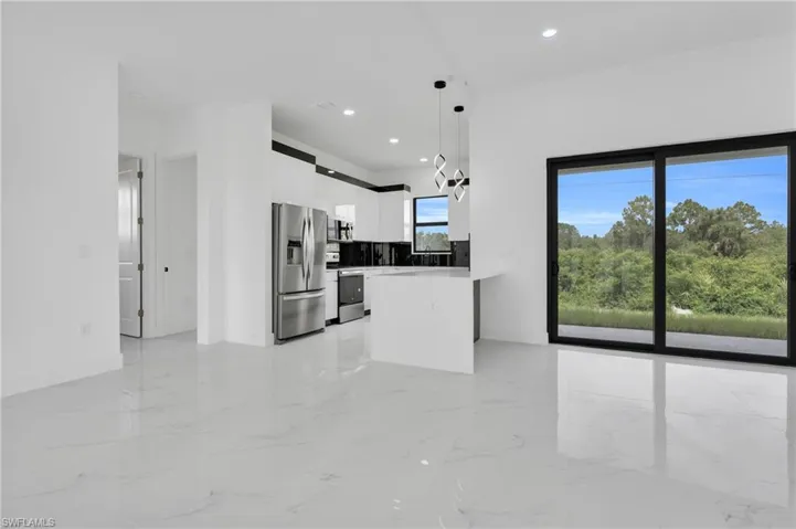 Kitchen featuring appliances with stainless steel finishes, modern cabinets, white cabinetry, a peninsula, and pendant lighting