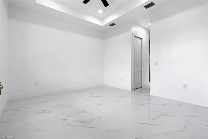 Spare room featuring ceiling fan, visible vents, baseboards, and a raised ceiling