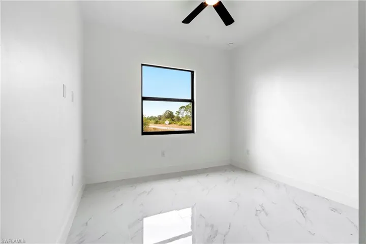 Empty room with a ceiling fan, baseboards, and marble finish floor