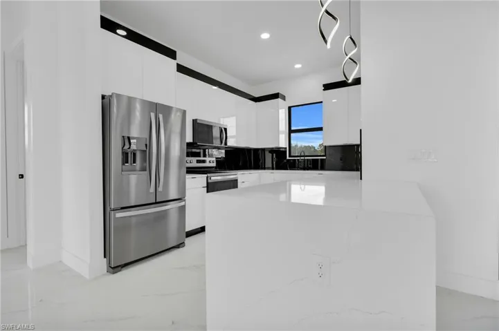 Kitchen featuring stainless steel appliances, modern cabinets, light marble finish flooring, white cabinetry, and recessed lighting