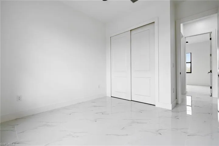 Unfurnished bedroom featuring baseboards, a closet, and marble finish floor