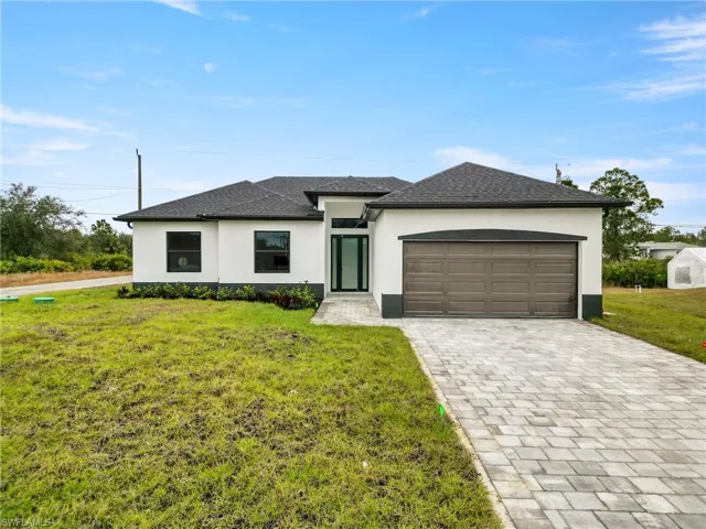 Prairie-style home with stucco siding, an attached garage, decorative driveway, and a front yard