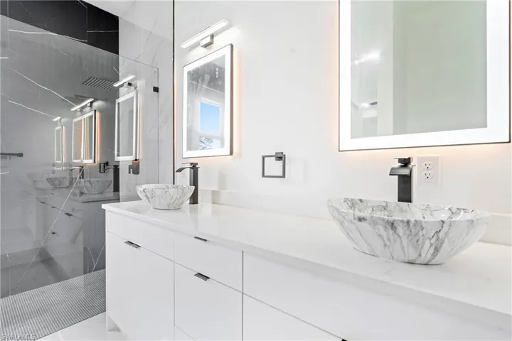 Bathroom featuring a sink, a marble finish shower, and double vanity