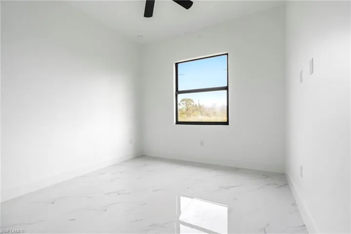 Spare room featuring baseboards, ceiling fan, and marble finish floor