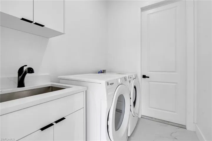 Laundry area featuring cabinet space, separate washer and dryer, and light marble finish flooring