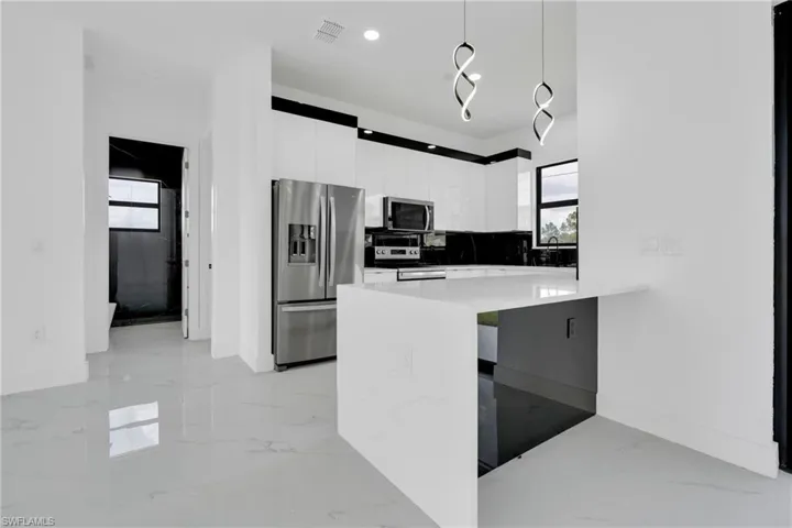 Kitchen with stainless steel appliances, modern cabinets, white cabinets, plenty of natural light, and recessed lighting