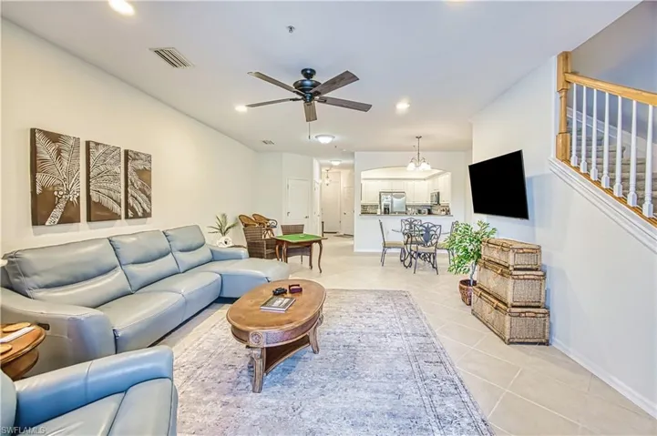Living area with a ceiling fan, light tile patterned floors, suspended lighting, and arched walkways