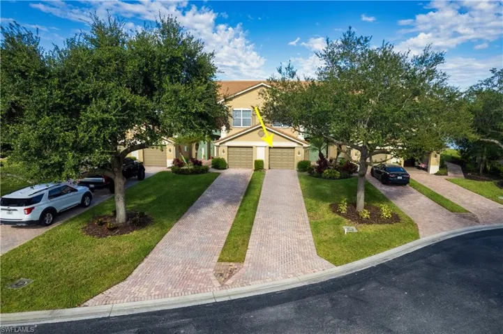 Obstructed view of property with decorative driveway, a front lawn, and a garage