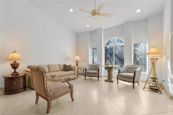 Living room with ceiling fan, a towering ceiling, and light tile patterned floors