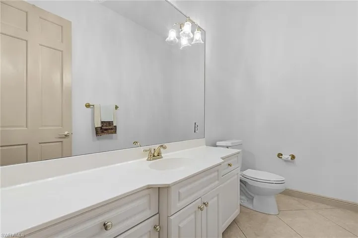 Powder Bath with tile patterned floors, toilet, and vanity
