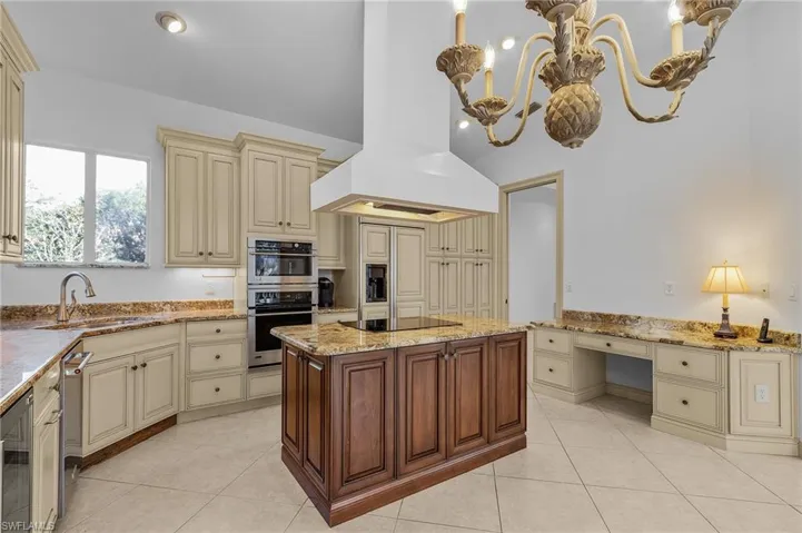 Kitchen featuring built in desk, sink, island exhaust hood, stainless steel appliances, and cream cabinets