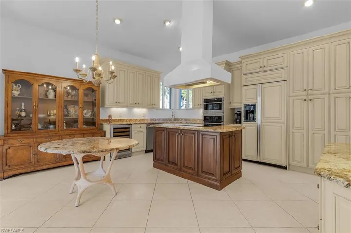 Kitchen with wine cooler, island exhaust hood, stainless steel appliances, and cream cabinets
