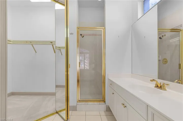 Guest Bathroom / walk in closet featuring an enclosed shower, vanity, and tile patterned floors