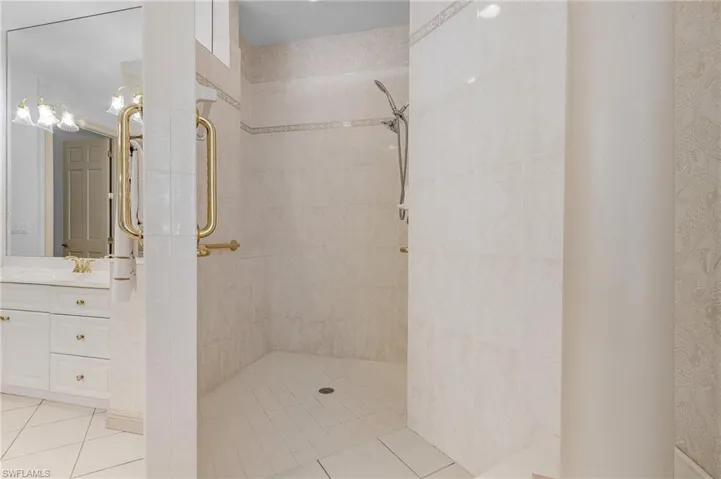 Bathroom with tile patterned floors, vanity, and a tile shower
