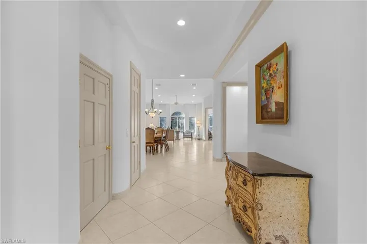 Hallway featuring crown molding, a chandelier, and light tile patterned floors