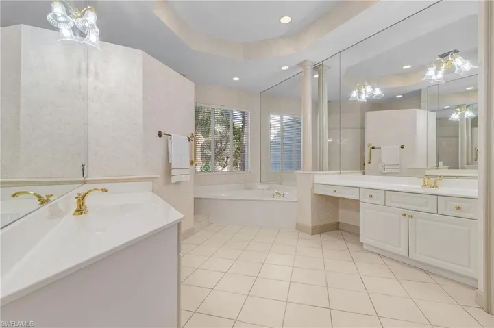 Bathroom with a tub to relax in, tile patterned floors, a raised ceiling, and vanity