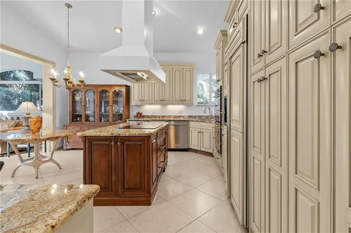 Kitchen featuring decorative light fixtures, island exhaust hood, a center island, stainless steel appliances, and cream cabinetry
