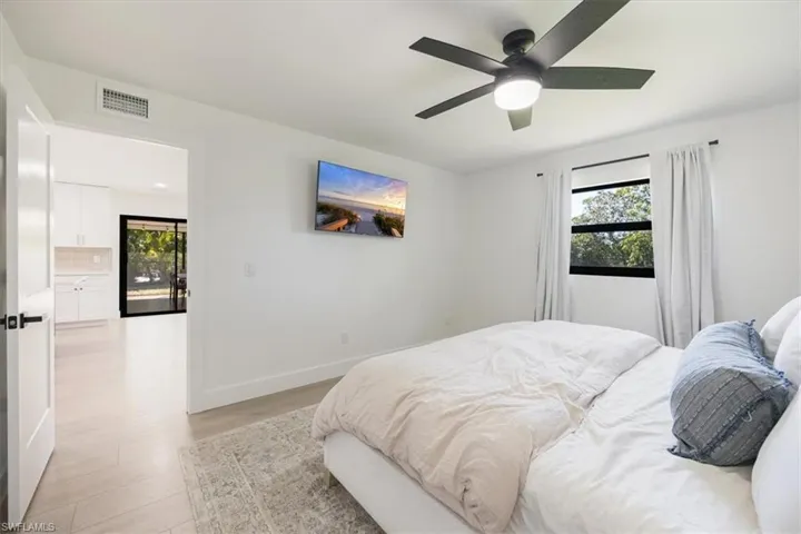 Bedroom featuring ensuite bathroom, light wood-type flooring, and ceiling fan