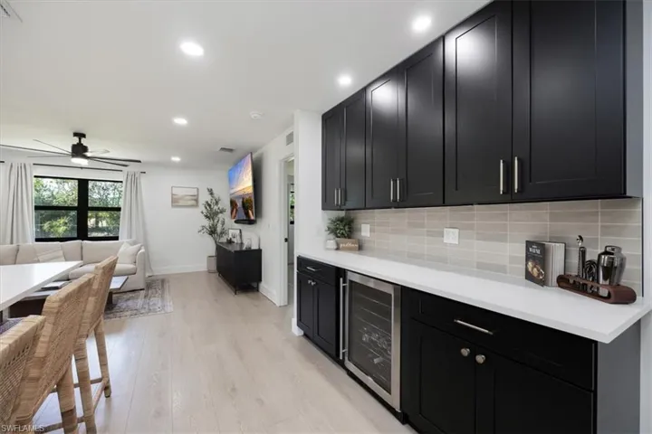 Kitchen with wine cooler, ceiling fan, decorative backsplash, and light hardwood / wood-style flooring