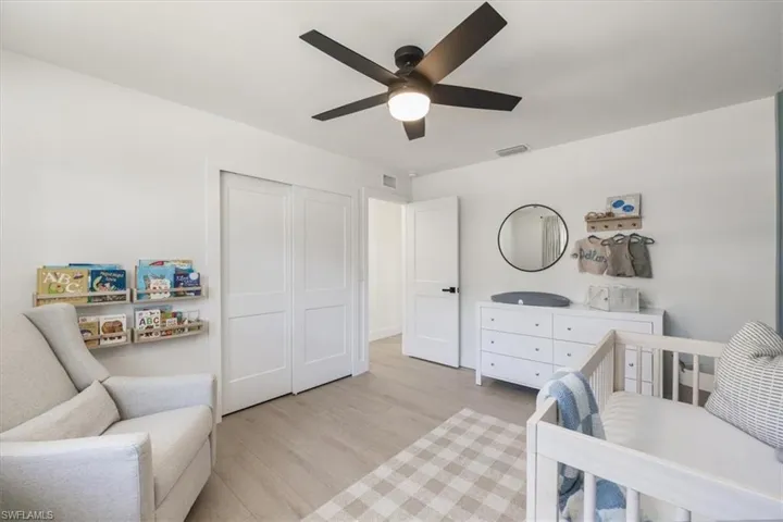 Bedroom with ceiling fan, light hardwood / wood-style floors, a closet, and a crib