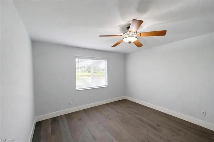 Spare room featuring dark wood-style flooring and ceiling fan