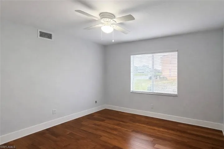Empty room featuring dark wood-type flooring and a ceiling fan