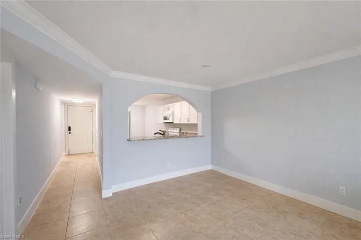 Empty room with ornamental molding and light tile patterned flooring