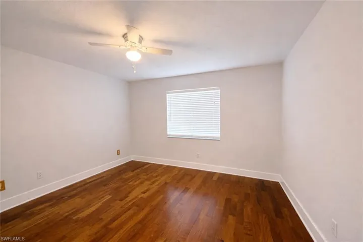 Empty room featuring dark wood-type flooring and a ceiling fan