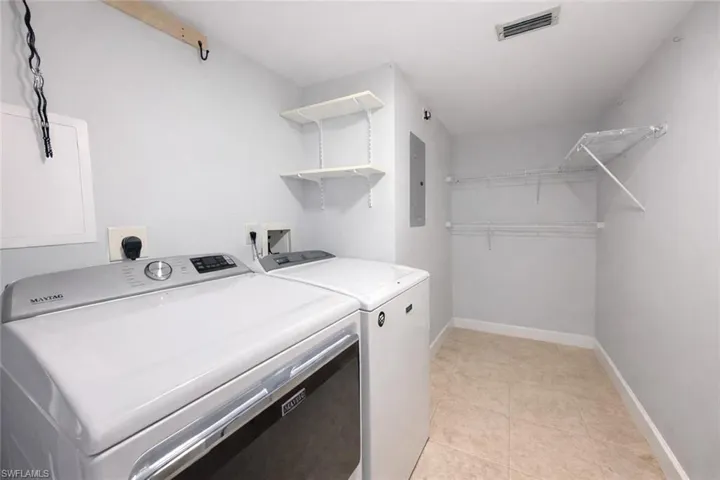 Laundry area with washer and clothes dryer, electric panel, and light tile patterned flooring