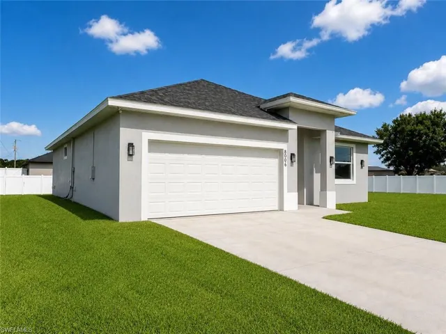 Contemporary stucco exterior featuring a two-car garage, mature landscaping, concrete driveway, and exterior wall sconces