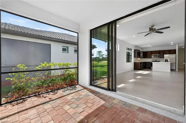 Unfurnished sunroom with a ceiling fan, exterior kitchen, and a patio area
