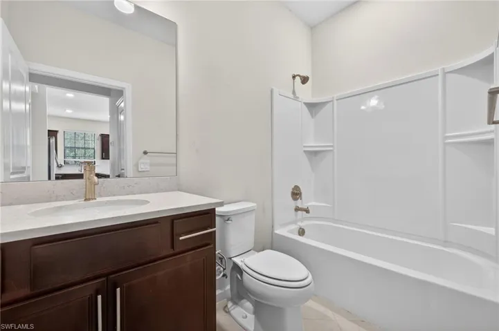 Bathroom with vanity, shower / bathtub combination, and light tile patterned flooring