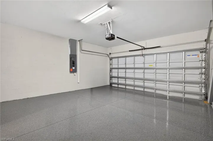 Garage with concrete block wall, electric panel, and a garage door opener