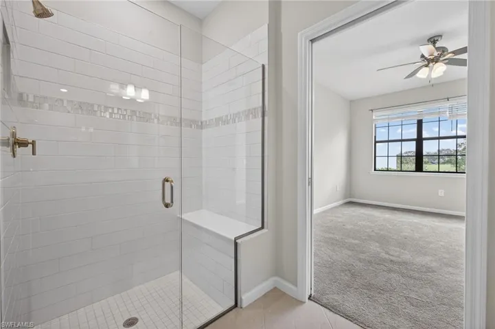 Primary Bathroom featuring a stall shower, ceiling fan, light colored carpet, and light tile patterned floors