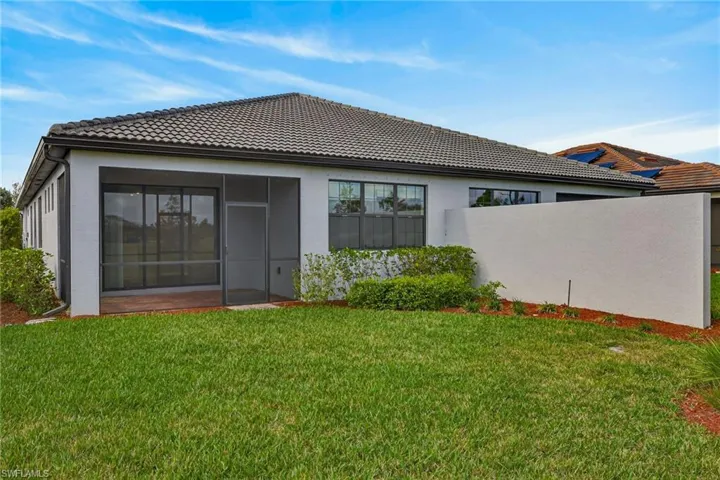 Back of property featuring stucco siding, a lawn, a sunroom, and a tiled roof