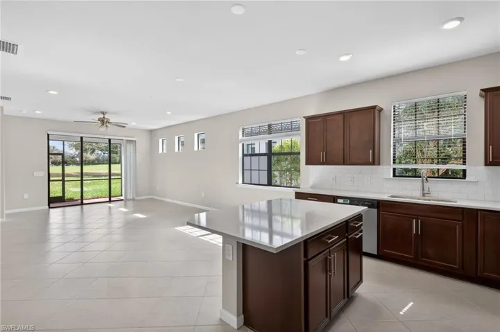 Kitchen with a kitchen island, light stone counters, light tile patterned floors, open floor plan, and stainless steel dishwasher