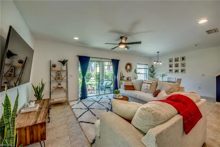 Tiled living room featuring ceiling fan with notable chandelier
