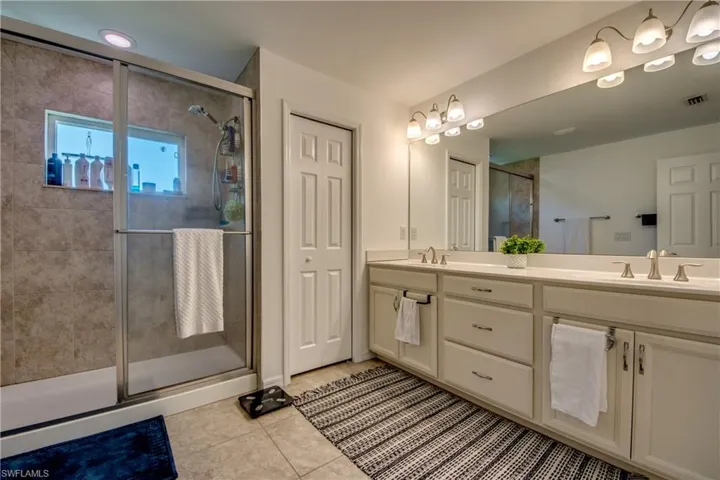 Bathroom featuring tile patterned floors, walk in shower, and dual bowl vanity