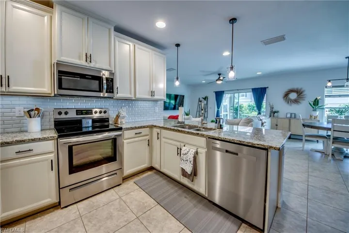 Kitchen with appliances with stainless steel finishes, pendant lighting, kitchen peninsula, and sink