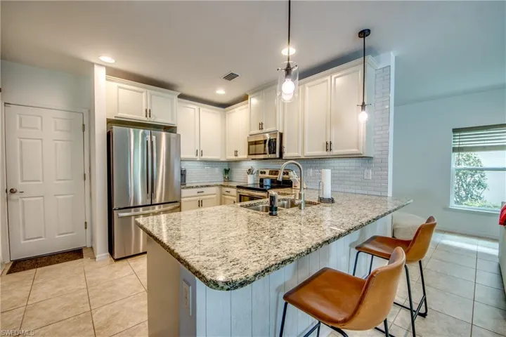 Kitchen with stainless steel appliances, pendant lighting, sink, kitchen peninsula, and backsplash