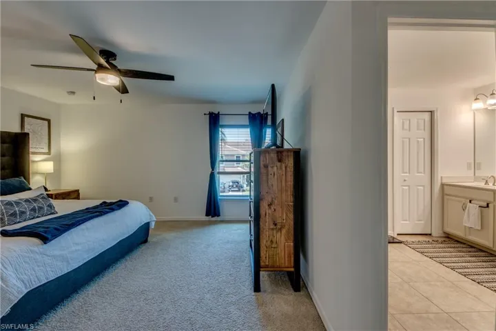 Bedroom featuring sink, light tile patterned flooring, connected bathroom, and ceiling fan
