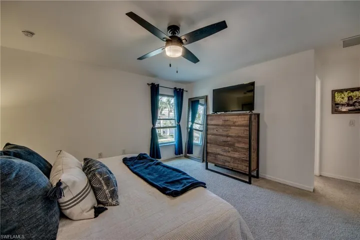 Carpeted bedroom featuring ceiling fan