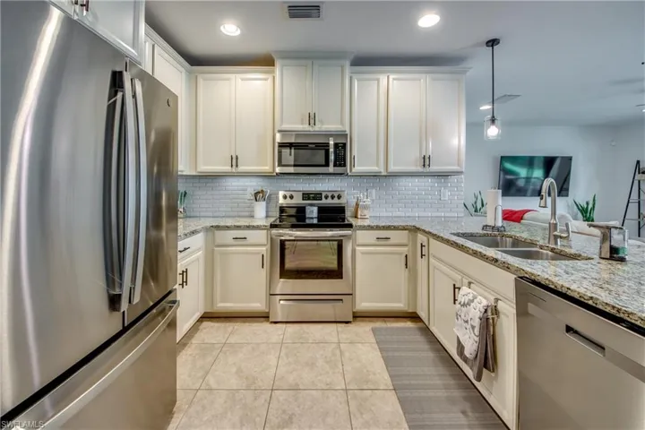 Kitchen with appliances with stainless steel finishes, decorative backsplash, light tile patterned floors, and sink