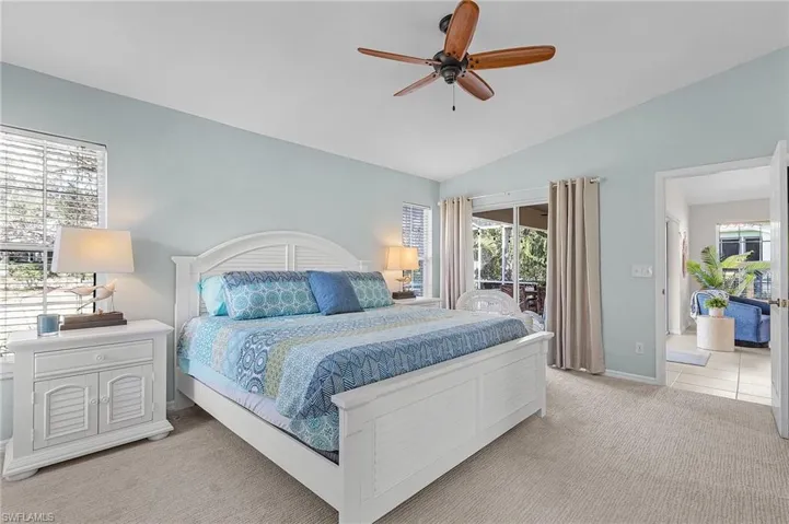 Carpeted bedroom featuring ceiling fan, lofted ceiling, access to exterior, and multiple windows