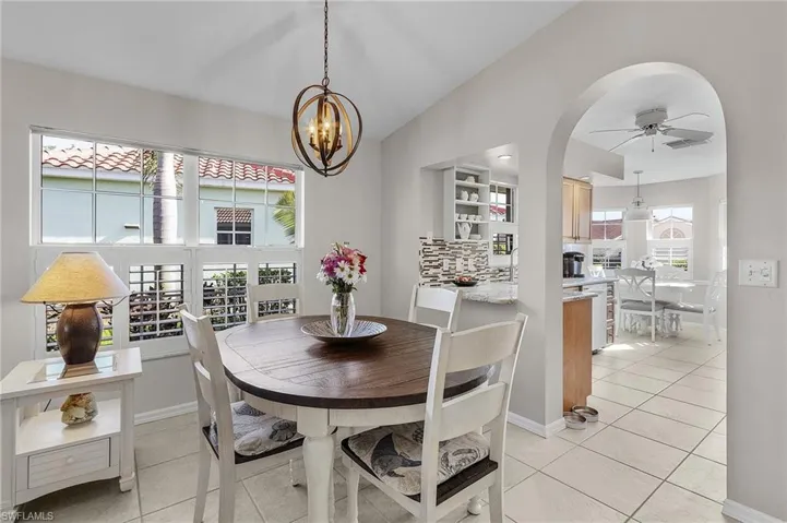 Tiled dining space featuring lofted ceiling and ceiling fan with notable chandelier